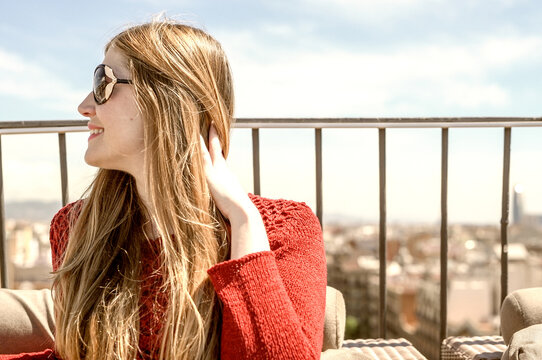 Blonde woman relaxing on a city rooftop seated on a sofa - Powered by Adobe
