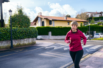 Woman jogging on a sidewalk in a residential neighborhood, maintaining an active and healthy lifestyle