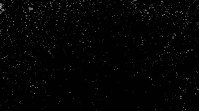 Wei&szlig;e runde Schneeflocken fliegen nach unten, isoliert auf schwarzem Hintergrund.