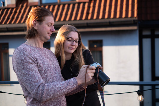 Couple enjoying photography together, reviewing images on camera outdoors, with warm sunlight illuminating their faces, creating a cozy and intimate atmosphere