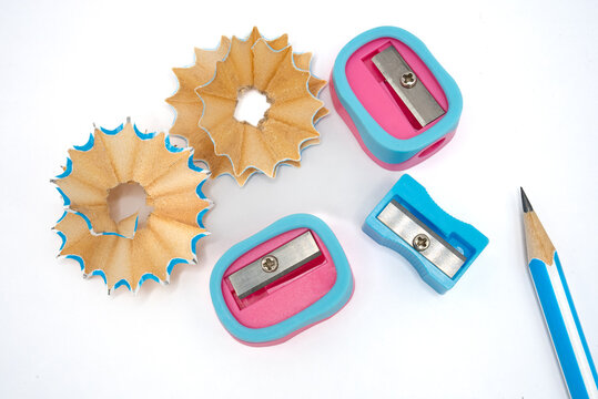 Pink and blue sharpeners with a blue pencil and curled wood shavings on a white background. Perfect for school campaigns, studying concepts, creativity and art themes. 