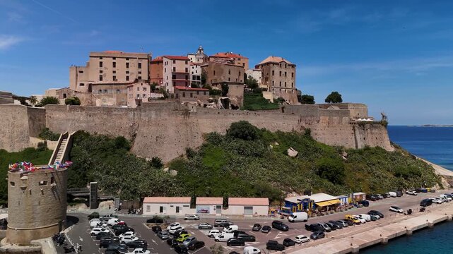 Expansive Aerial Drone Pan Across the Historic Genoese Calvi Citadel Fortress, Above the Town and Northwest Corsican Mediterranean Coast on a Sunny Day.