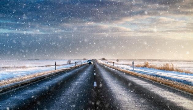 Car drives on snowy road under cloudy sky, creating serene winter landscape