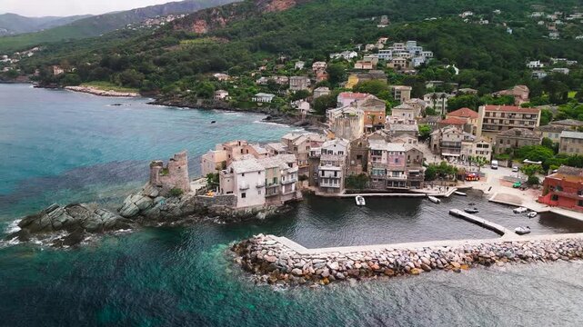 Aerial Drone Shot Gliding Past the Ruined Genoese Tower and Historic Port of Erbalunga Village on the Overcast Eastern Coast of Cap Corse, Corsica, France.