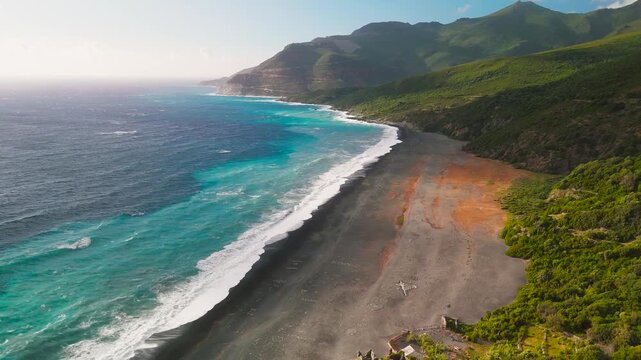 Cinematic Aerial Drone Descent towards the Unique Dark Grey Sand of Deserted Plage de Nonza Beach, Cap Corse, Corsica, France.