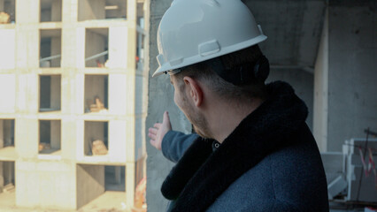 A construction worker in a hard hat looking up while standing inside a building 