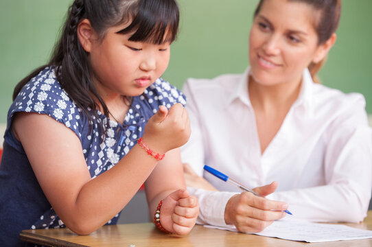 Asian kid at school learning math with teacher