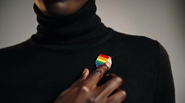 Confident person with pride symbol on black turtleneck against studio background