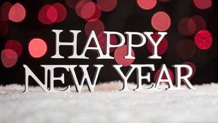 Happy new year silver lettering on snow with festive red bokeh lights creating a celebratory holiday atmosphere for seasonal greetings