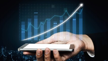 A business person holds a smartphone displaying a digital graph depicting an upward trend in financial data analysis against a city skyline at night. Copula