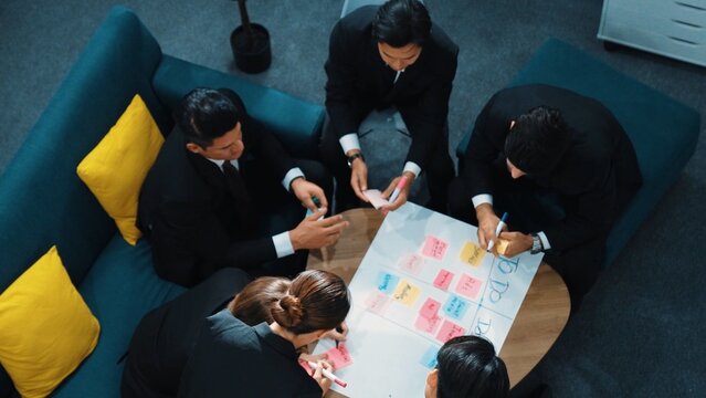 Top view of smart business team write marketing plan and putting stick notes on mind map. Group of happy business people brainstorm financial idea and planning strategy at meeting room. Directorate.
