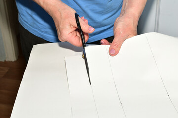 A cutter makes a pattern for fabric by cutting strips of paper.