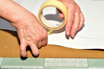 The cutter makes a pattern for the fabric by gluing the parts of the pattern together with tape.