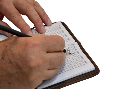 A man scribbles something on the pages of a notebook with a pencil.