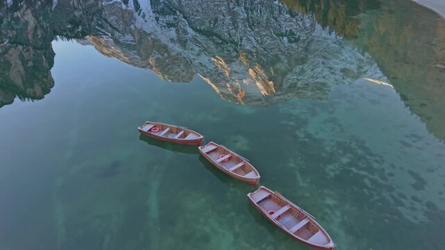 Lake Braies in Italy with alpine reflections and rowboats, aerial view in Dolomites