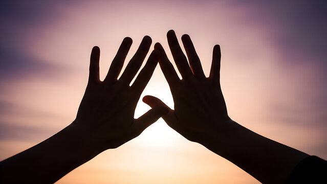 Hands creating a heart shape silhouette against a sunset background  