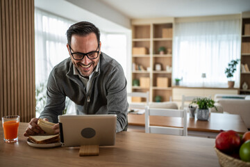 Man enjoying snack communicating on tablet during video call