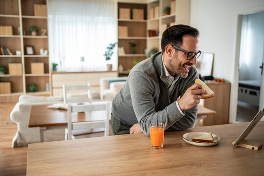 Man smiling having breakfast during video call at home