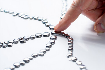 Hand Pushing Small Silver Mercury Drops Together with Finger on White Surface Showing Connectivity Concept Close up Shot