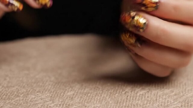Decorative floral nail art on manicured fingers with warm autumnal colors
