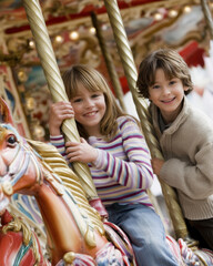 Two smiling children on colorful carousel horse, joyful expression and playful atmosphere captured in soft light