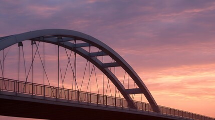 Fototapeta premium A modern arch bridge s steel cables and structure are silhouetted against a vibrant pink and purple sunset sky