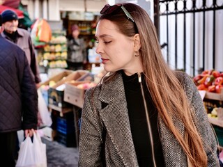 Woman choosing fresh vegetables and produce at an outdoor or farmer's market. Concept of healthy eating, local shopping, organic food, and sustainable lifestyle.