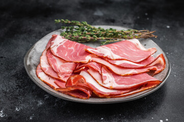 Sliced gammon displayed with pink salt and metal fork on a dark textured backdrop perfect for gourmet food photography.