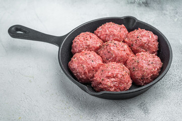 Raw kofta style meatballs seasoned in skillet over rustic board ideal for culinary, kitchen and ingredient stock photography.