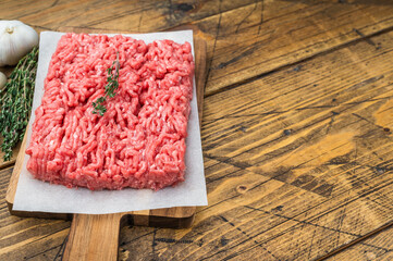 Uncooked minced veal and mutton meat slab with herbs, garlic and salt on wooden board highlighting raw texture for culinary and food prep visuals.