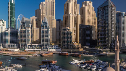 Fototapeta premium Luxury yachts parked on the pier in Dubai Marina bay with city aerial view timelapse