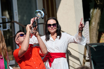 Man playing trumpet and woman dancing outdoors in bright sunlight