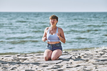 Young woman practicing pranayama breathing and body tapping on Baltic Sea beach