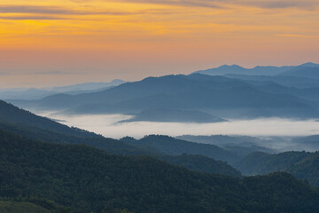 Mountain landscape with misty valley and colorful sunrise sky creating peaceful and serene atmosphere in nature