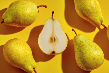 Ripe yellow pears with pear half on bright yellow background, minimal food concept