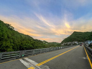 Stunning dawn sky in Wulai, New Taipei City, Taiwan. Dramatic golden and orange clouds illuminate the morning sky above silhouetted mountain ranges and forest.