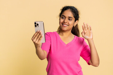Indian woman energetically waves, filming herself talking and smiling, recording an engaging video. Arabian girl expresses cheerful interaction, social media blogging, lively communication positivity