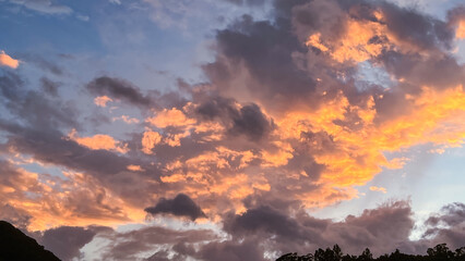 September dawn in Wulai, New Taipei City, Taiwan: vivid orange clouds above silhouetted trees and hills.