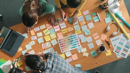 Naklejka premium Time lapse of business team with casual outfit looking laptop screen and sharing idea. Aerial view of manager working and checking color palette at table with sticky notes and headphone. Symposium.