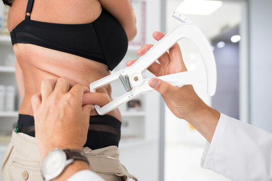 Nutrition speacialist doctor woman measuring abdominal body fat on a woman. Belly chubby paunchy sport recreation health care lose belly fat concept.