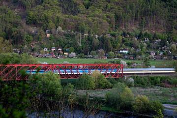 High-speed train crossing the red railway bridge near Černo&scaron;ice and V&scaron;enory, Czech Republic over the Berounka river