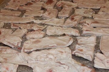 Display of raw pork belly pieces arranged on a surface for food preparation in a kitchen setting