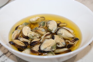 Fresh oysters served in a bowl with olive oil and herbs on a kitchen countertop