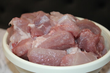 Freshly cut pork pieces ready for cooking in a white bowl