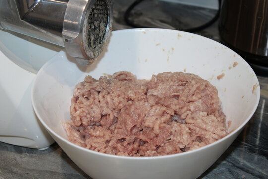 Ground meat preparation in a kitchen with a meat grinder on a countertop during a cooking session