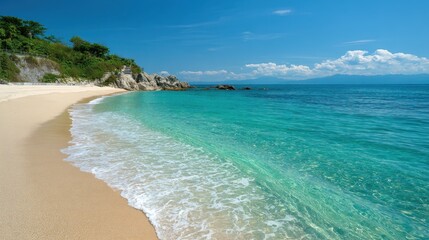 Soft sandy beach stretches along a calm ocean with clear turquoise water under a bright blue sky. Gentle waves lap at the shore creating a tranquil atmosphere.