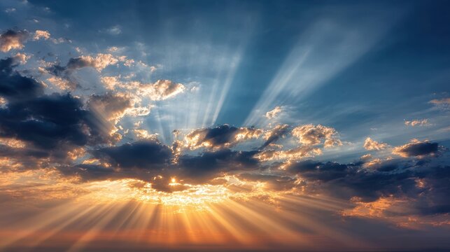 Bright sunrays pierce through fluffy clouds as the sun sets on the horizon. The sky is filled with stunning colors that create a peaceful scenery.