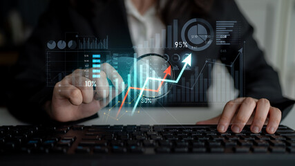A business professional engages with digital graphs and statistics on a keyboard, illustrating...