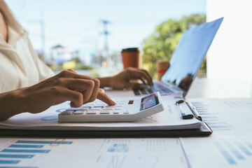 Obraz premium A person reviews financial charts while using a calculator and laptop on a desk, focusing on data analysis and business planning.