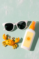 Summer Flat Lay with Sunscreen, Sunglasses and Toy Crab on Mint Background